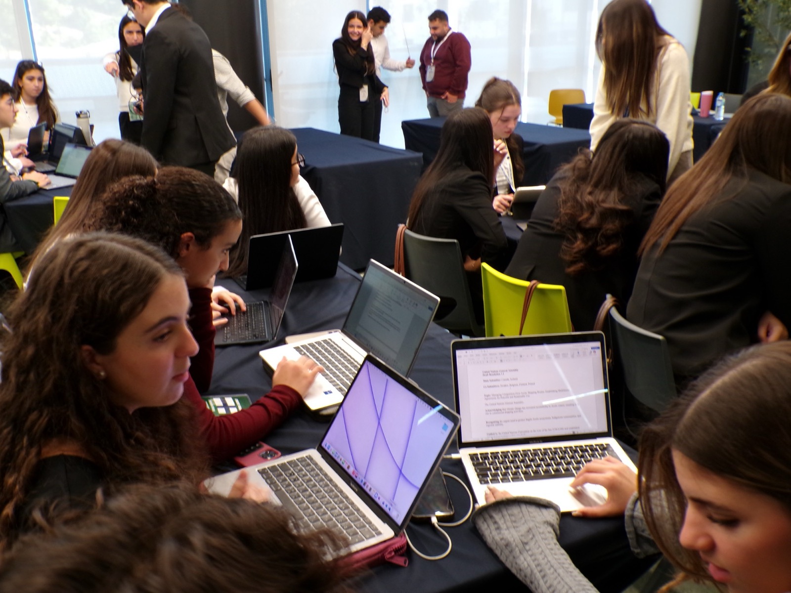 Delegates working together on laptops, drafting a resolution
